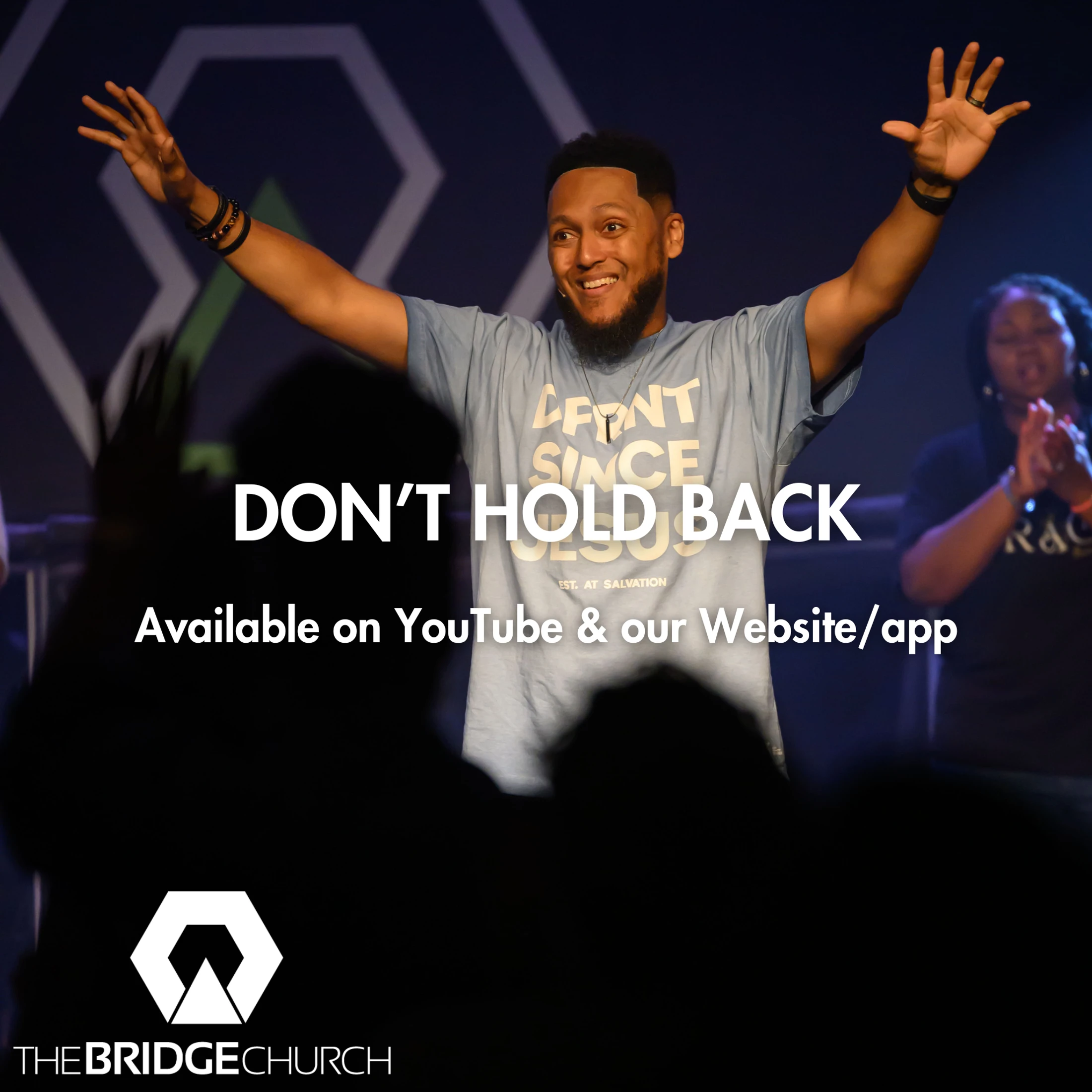 A man smiles and worships with his arms raised on stage. The text says "Don't Hold Back" and lists YouTube and a website/app as available platforms.