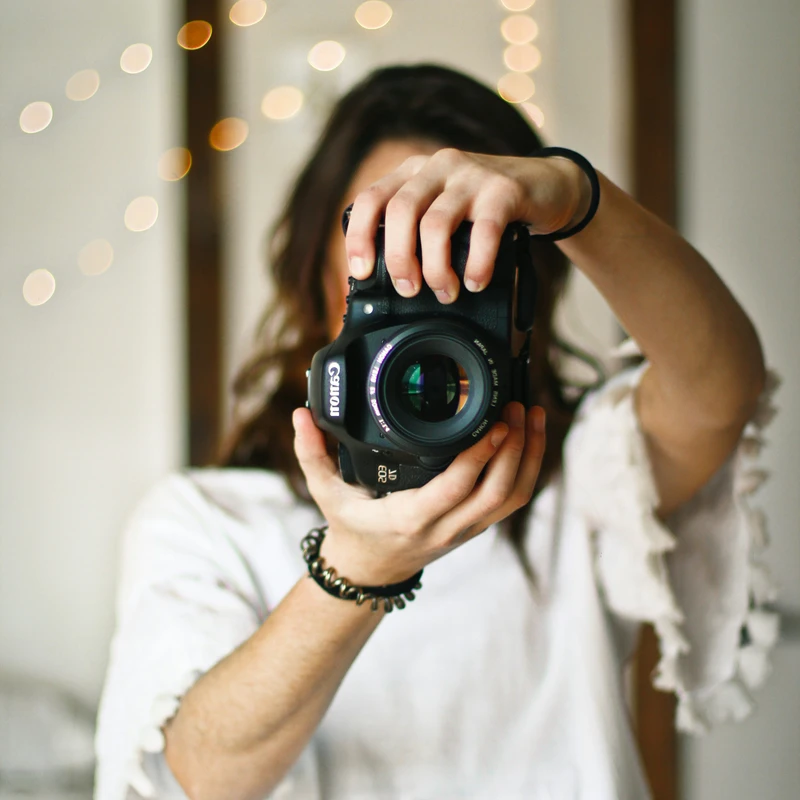 woman holding black DSLR camera