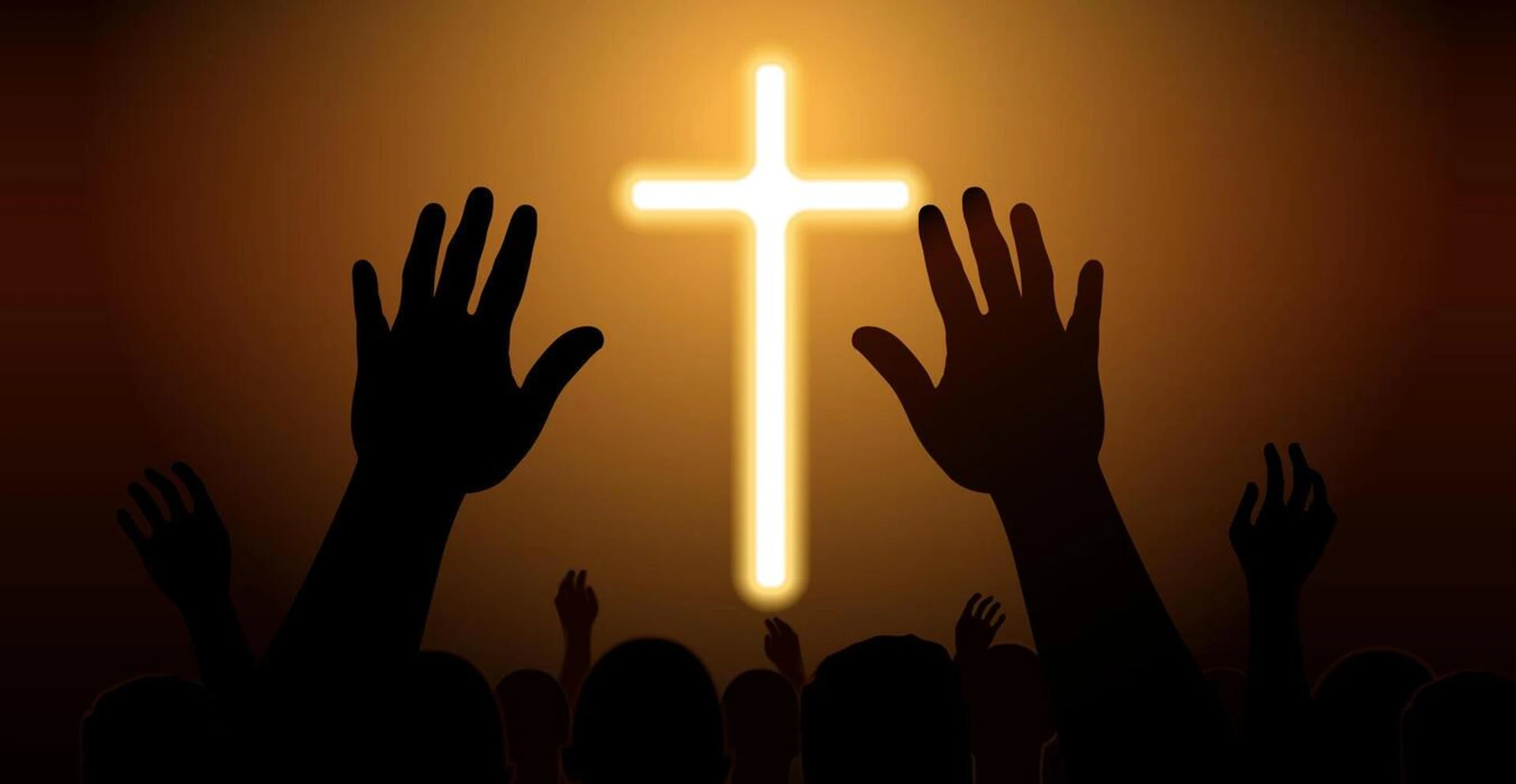 Silhouettes of a crowd raising their hands in worship towards a large, brightly glowing Christian cross against a dark, golden background.