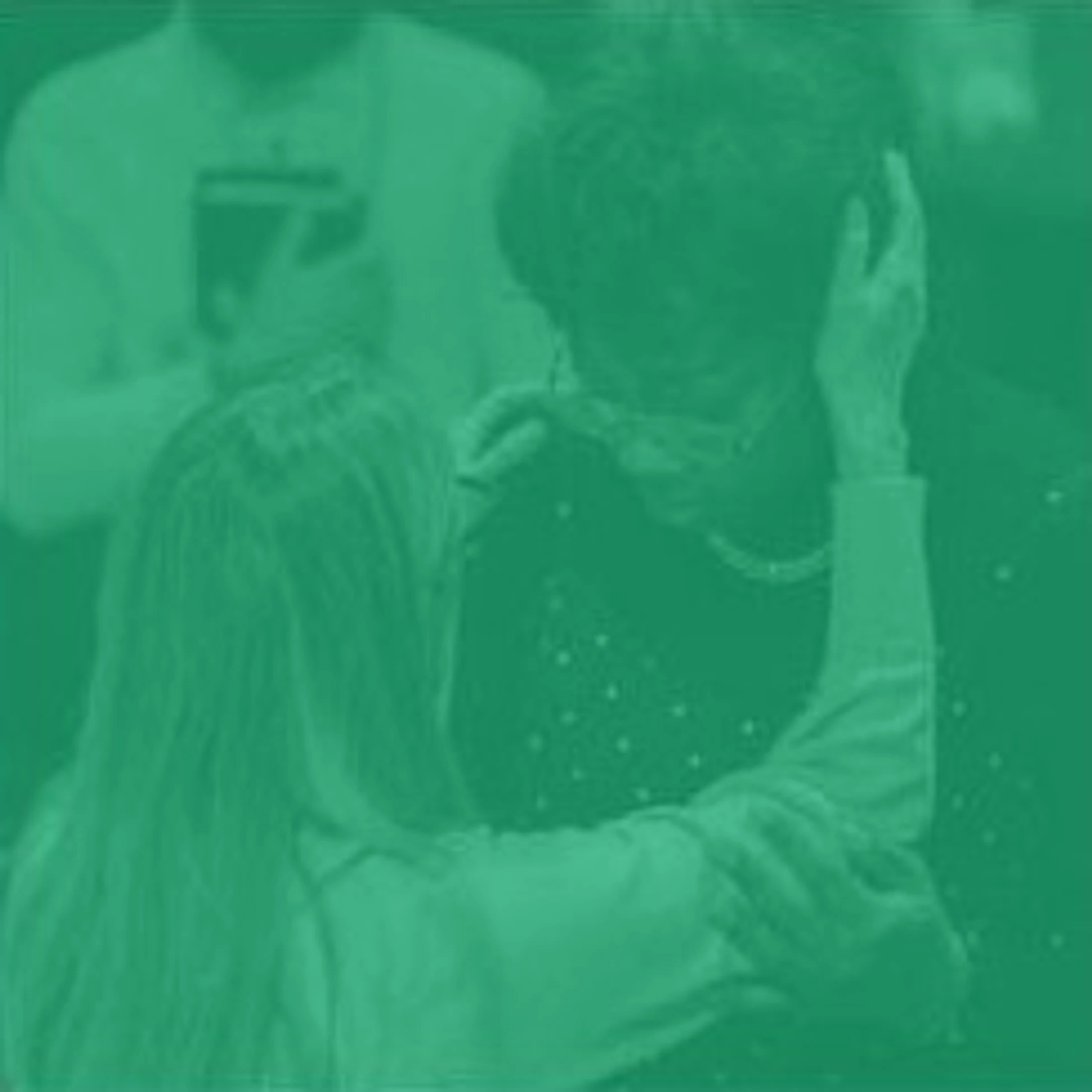 A green-tinted image showing a person with long hair, seen from behind, gently embracing and comforting another person with short hair.