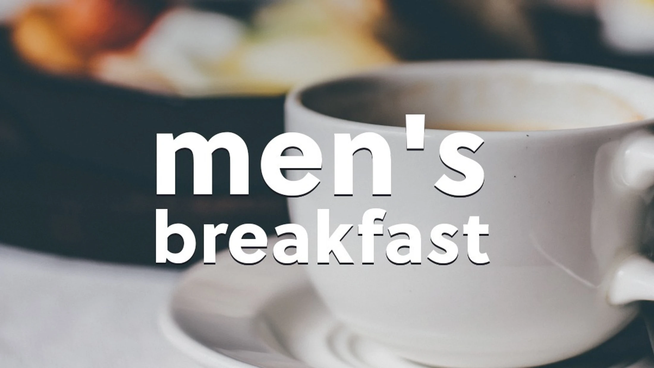 A close-up shot of a white coffee cup on a saucer with the words 'men's breakfast' in white text overlayed. A plate of food is blurred in the background.