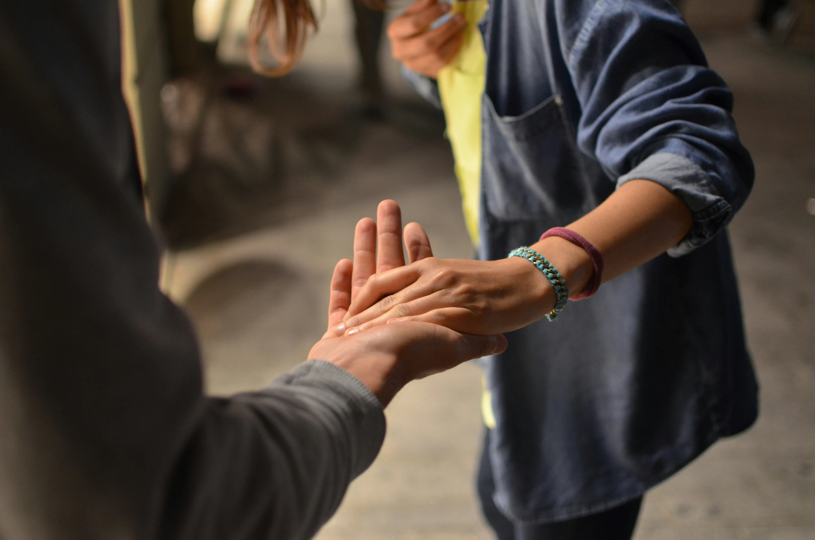 A close-up of two people's hands, with one person's hand resting gently in the open palm of the other, symbolizing support and connection.