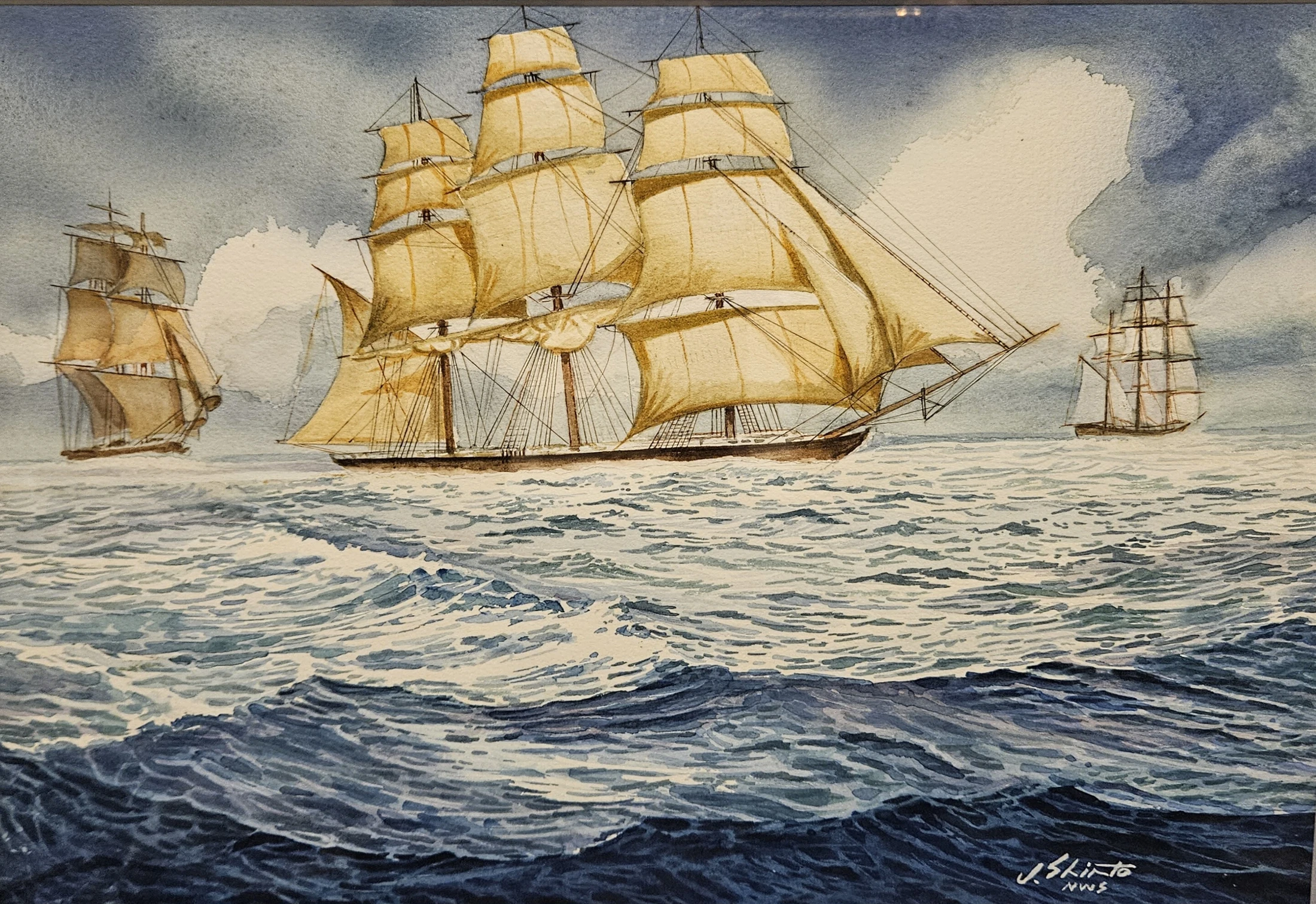A dramatic watercolor painting shows three tall ships with large tan sails sailing on a rough, dark blue ocean under a cloudy, grey sky.