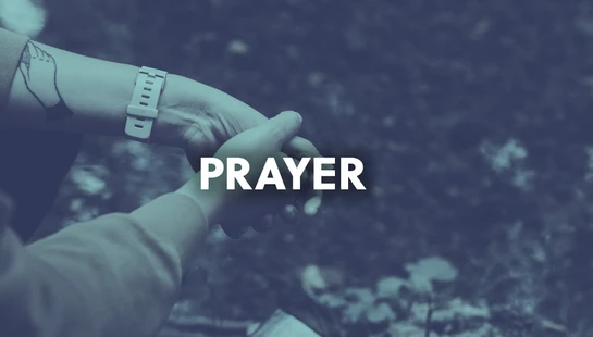 A close-up of two people holding hands, with the word 'PRAYER' in bold white text over them. The image has a cool, blue color filter.