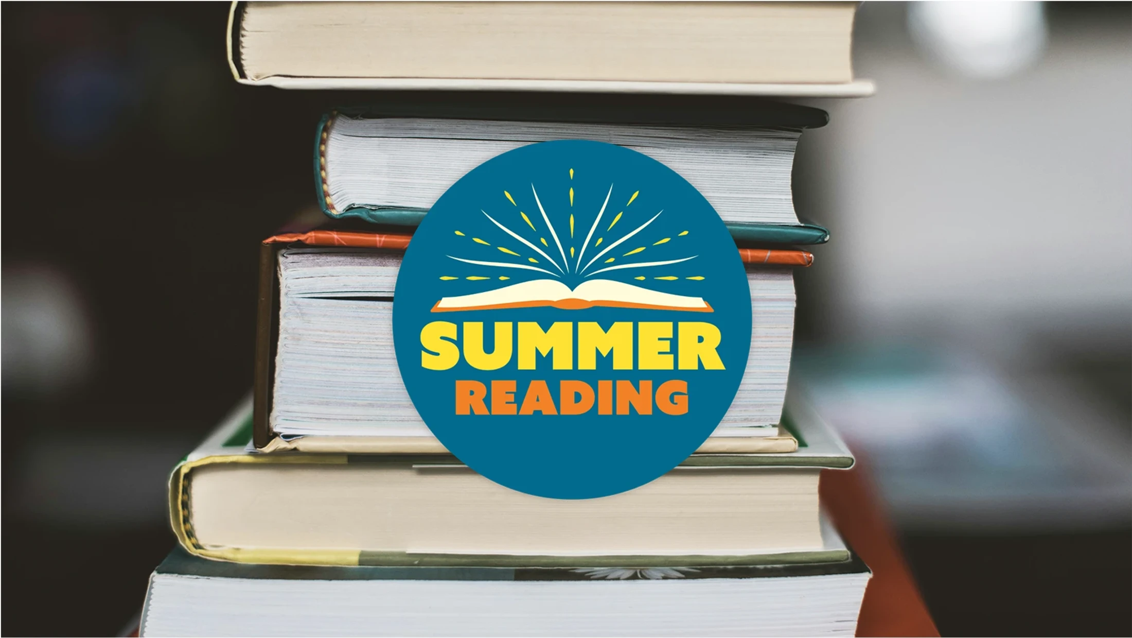 A stack of books with a blue circular graphic that says 'Summer Reading' with an illustration of an open book.