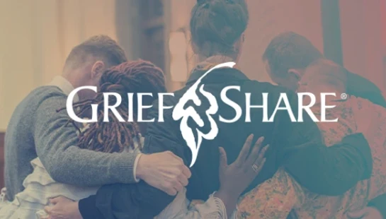 A diverse group of people seen from behind, huddled in a supportive embrace. The GriefShare logo is overlaid in the center of the image.