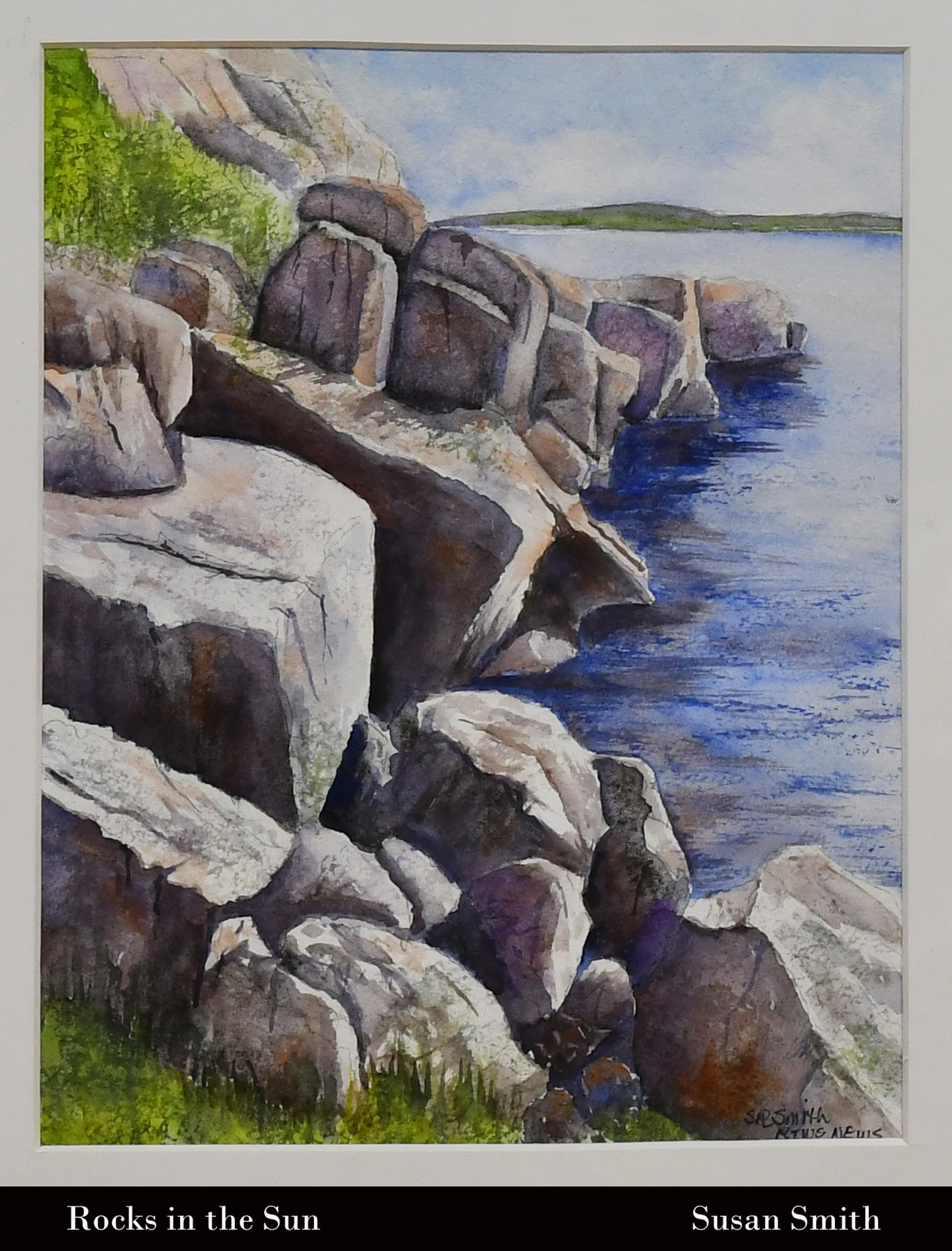 A watercolor painting of a rocky coastline. Large, sunlit grey boulders line the edge of deep blue water, with a distant green shore under a pale sky.