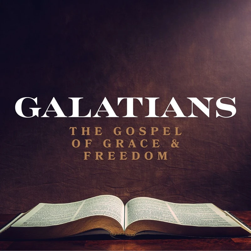 An open Bible sits on a dark wooden table, illuminated by a spotlight. Above the book is the text 'Galatians, The Gospel of Grace & Freedom'.