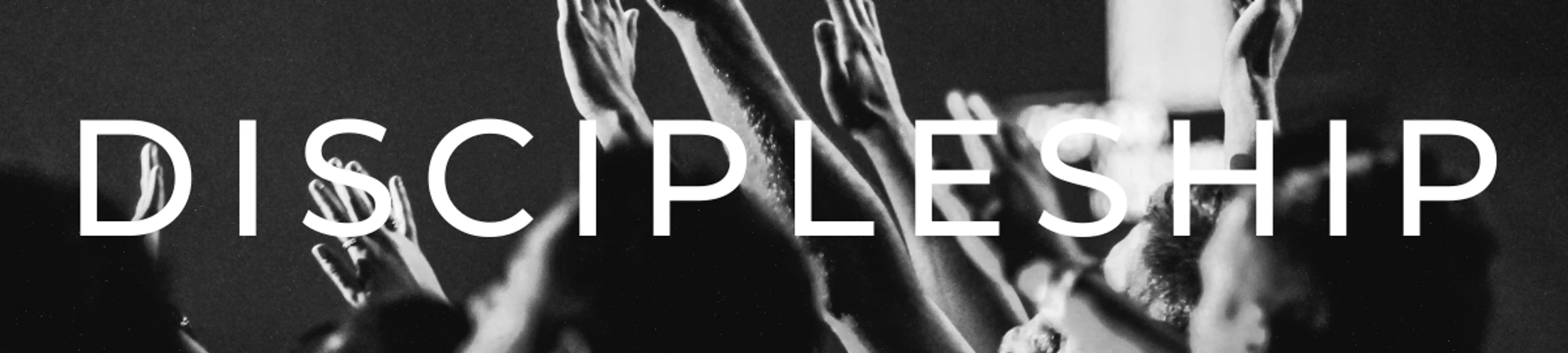 A black and white banner with the word DISCIPLESHIP in white text over a photo of a crowd of people raising their hands in worship.