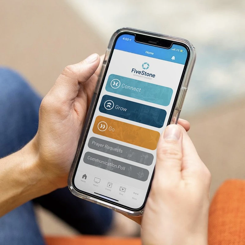 A close-up of hands holding a smartphone displaying the FiveStone Community Church app, showing options like Connect, Grow, Go, and Prayer Requests.