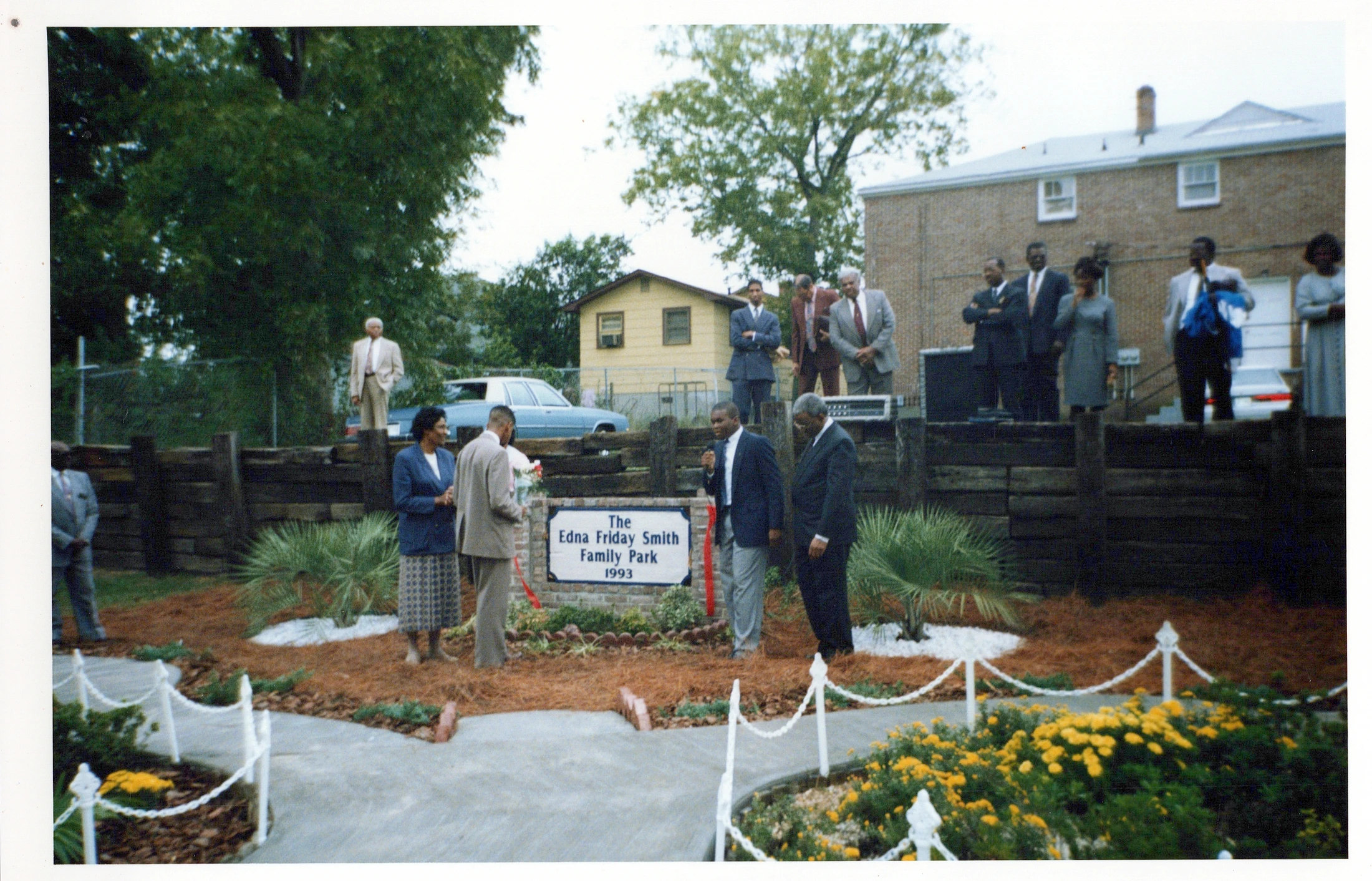 A group of African American men and women in suits and dresses gathered outdoors for the dedication of The Edna Friday Smith Family Park in 1993.