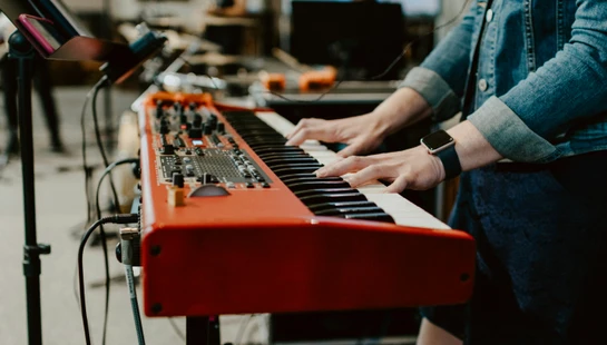 person playing red and black electric piano