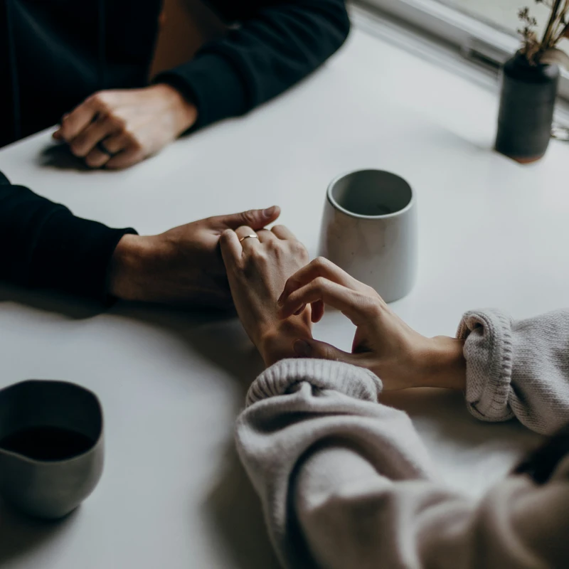 two people holding hands at table