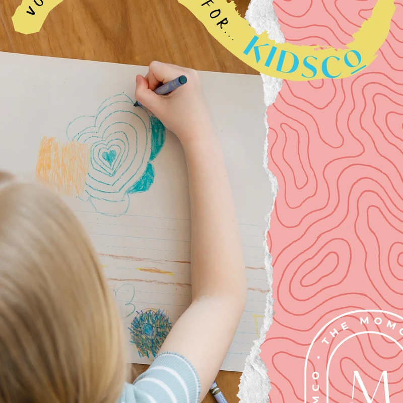 A graphic asking for volunteers for KidsCo, featuring an overhead view of a child drawing a heart with crayons on a wooden table.