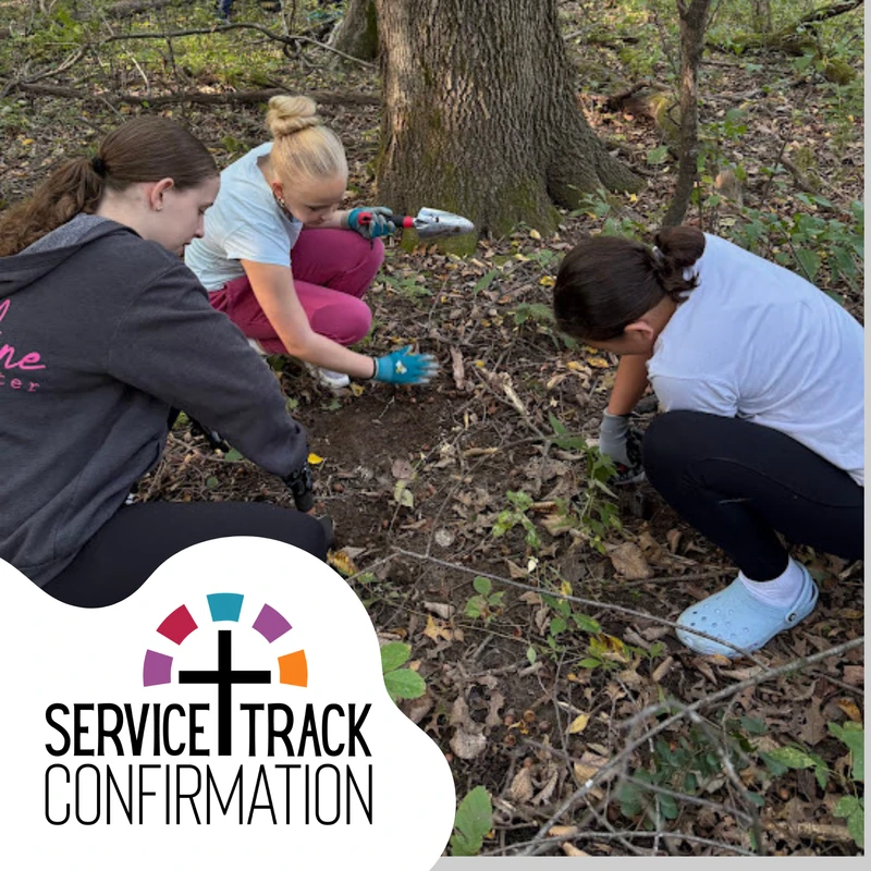 Three young women kneel in a wooded area, digging in the dirt with small shovels during a Service Track Confirmation volunteer event.