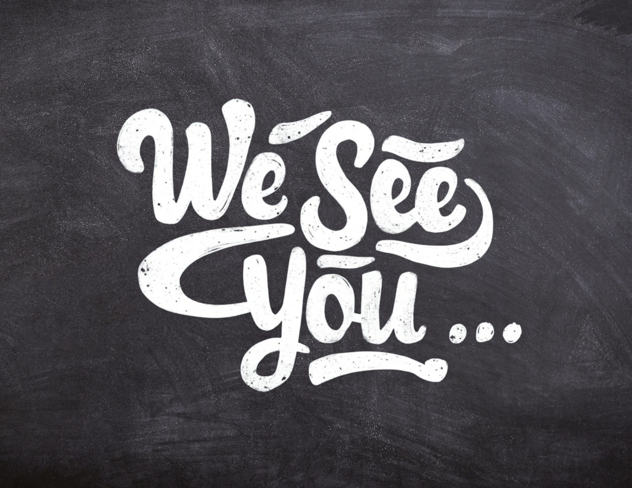 The phrase 'We See You...' written in a white, stylized script on a dark, textured background resembling a chalkboard.