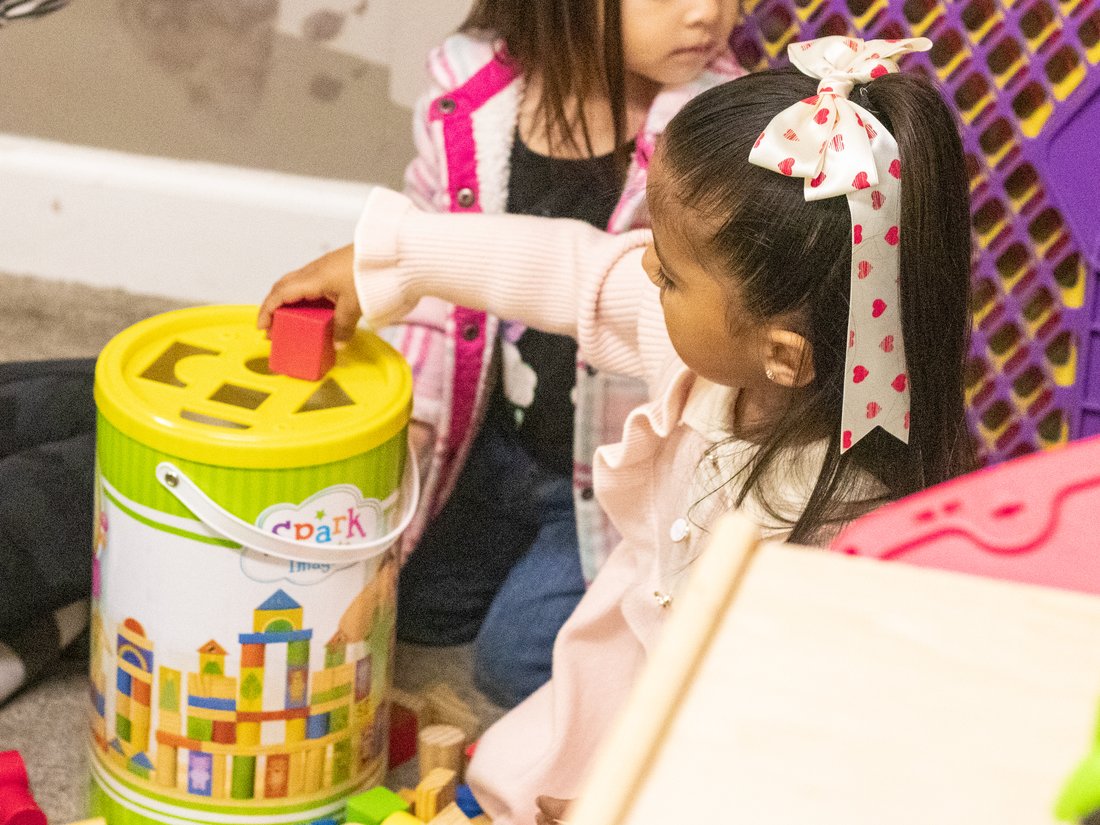 A little girl placing a shape into a Spark shape-sorter toy