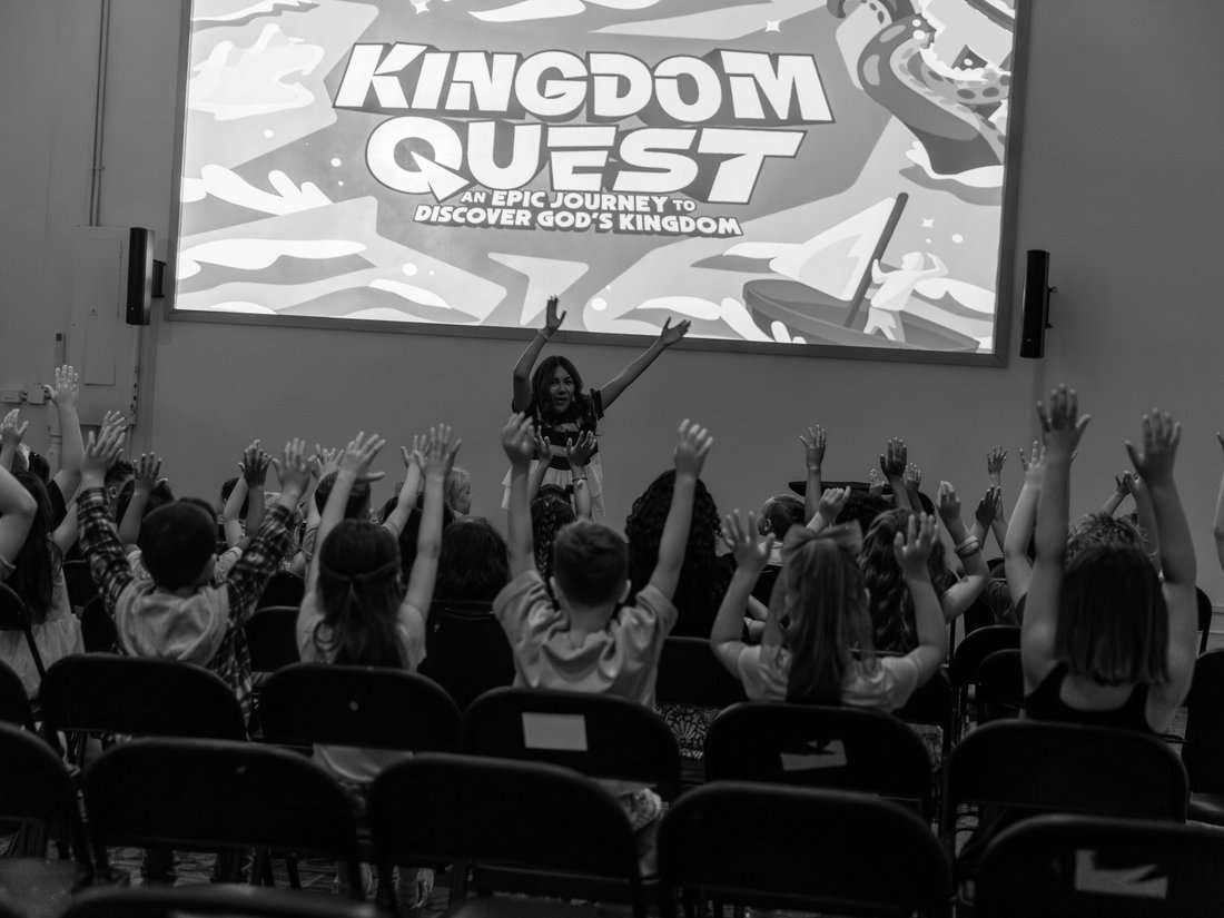 Kids raising their hands during a Kingdom Quest worship service