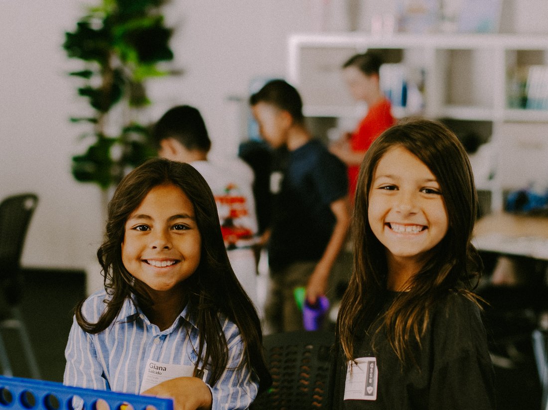 Two smiling Discovery Kids girls playing Connect Four together