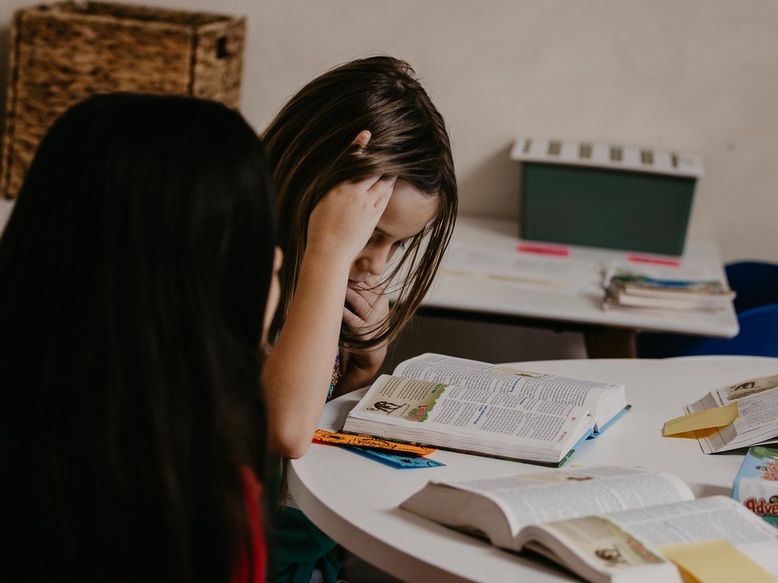 A girl reading her Bible at a table during Discovery Kids