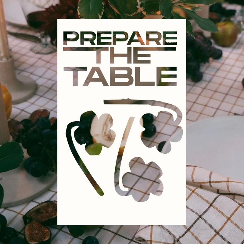 A rustic dinner table set with fruit, candles, and wine, with a graphic overlay in the center that reads 'Prepare The Table'.