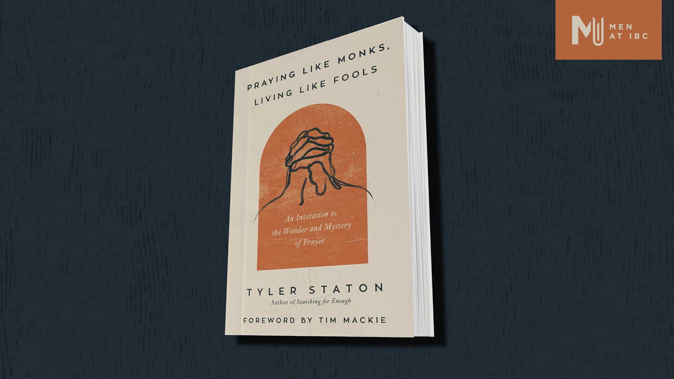The book 'Praying Like Monks, Living Like Fools' by Tyler Staton on a dark, textured background, with the 'Men at IBC' logo in the top right corner.