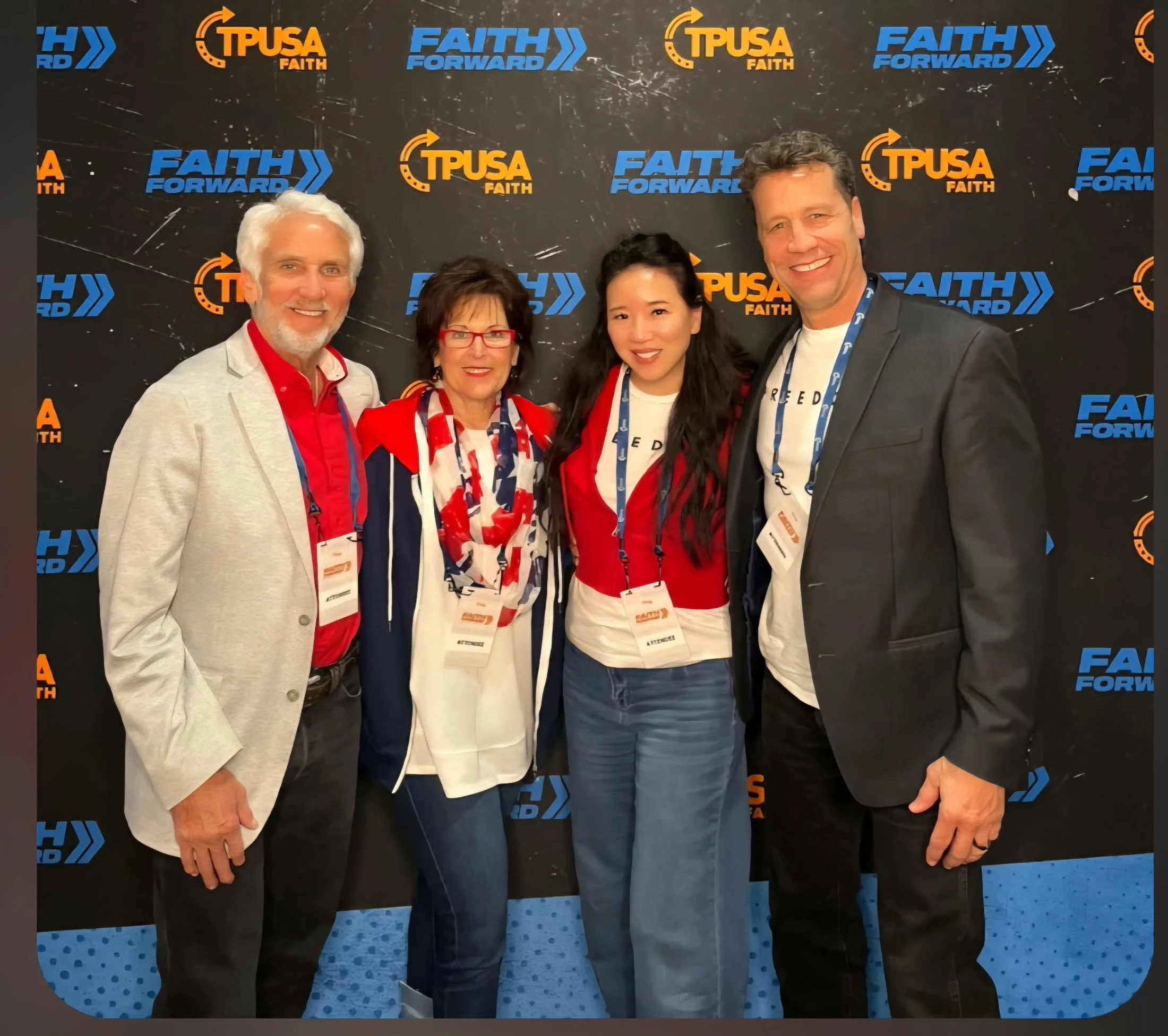 A group of four attendees, two men and two women, smiling for a photo in front of a backdrop for the TPUSA Faith Forward conference.
