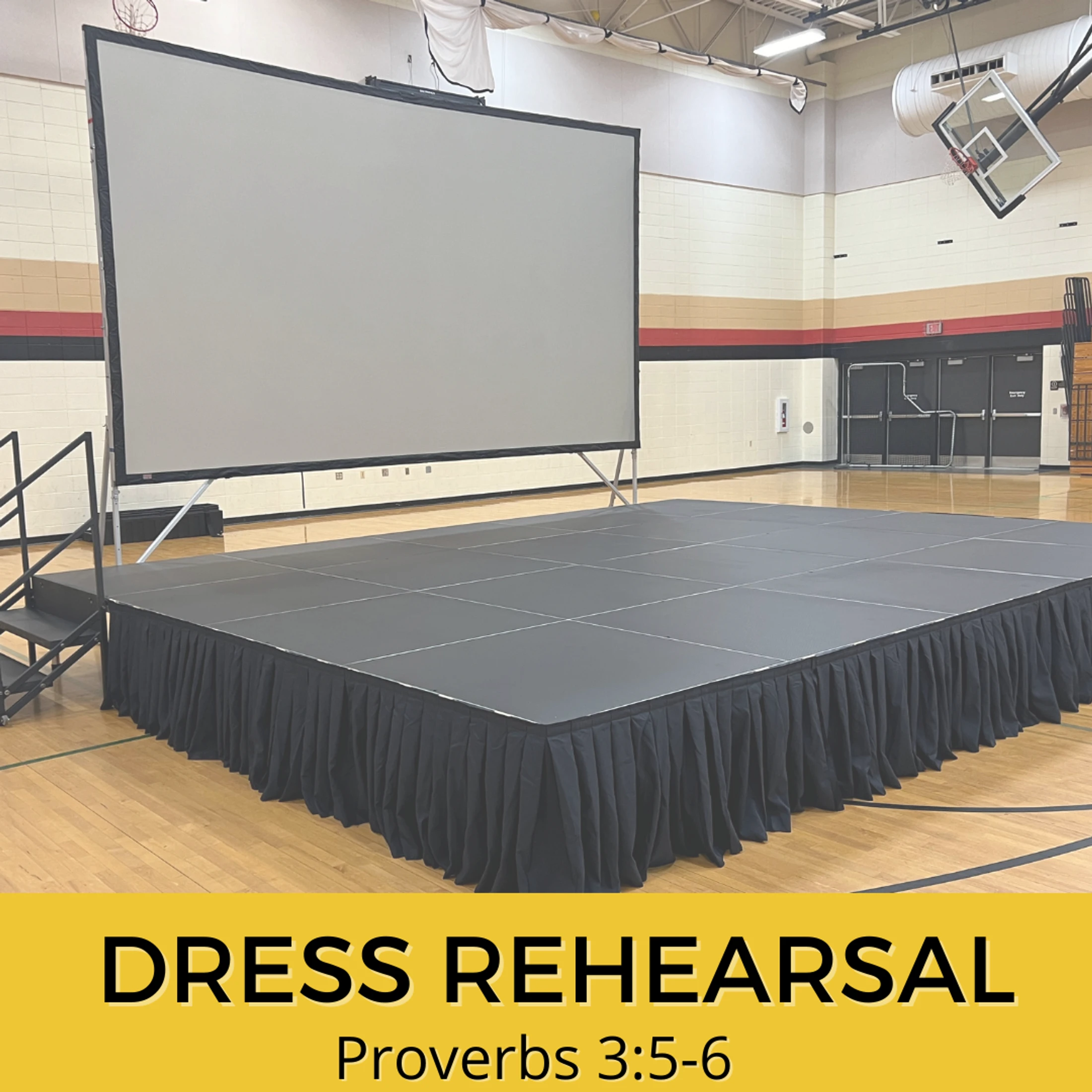 An empty black stage with a large projection screen is set up in a gymnasium. A yellow banner at the bottom reads 'Dress Rehearsal, Proverbs 3:5-6'.