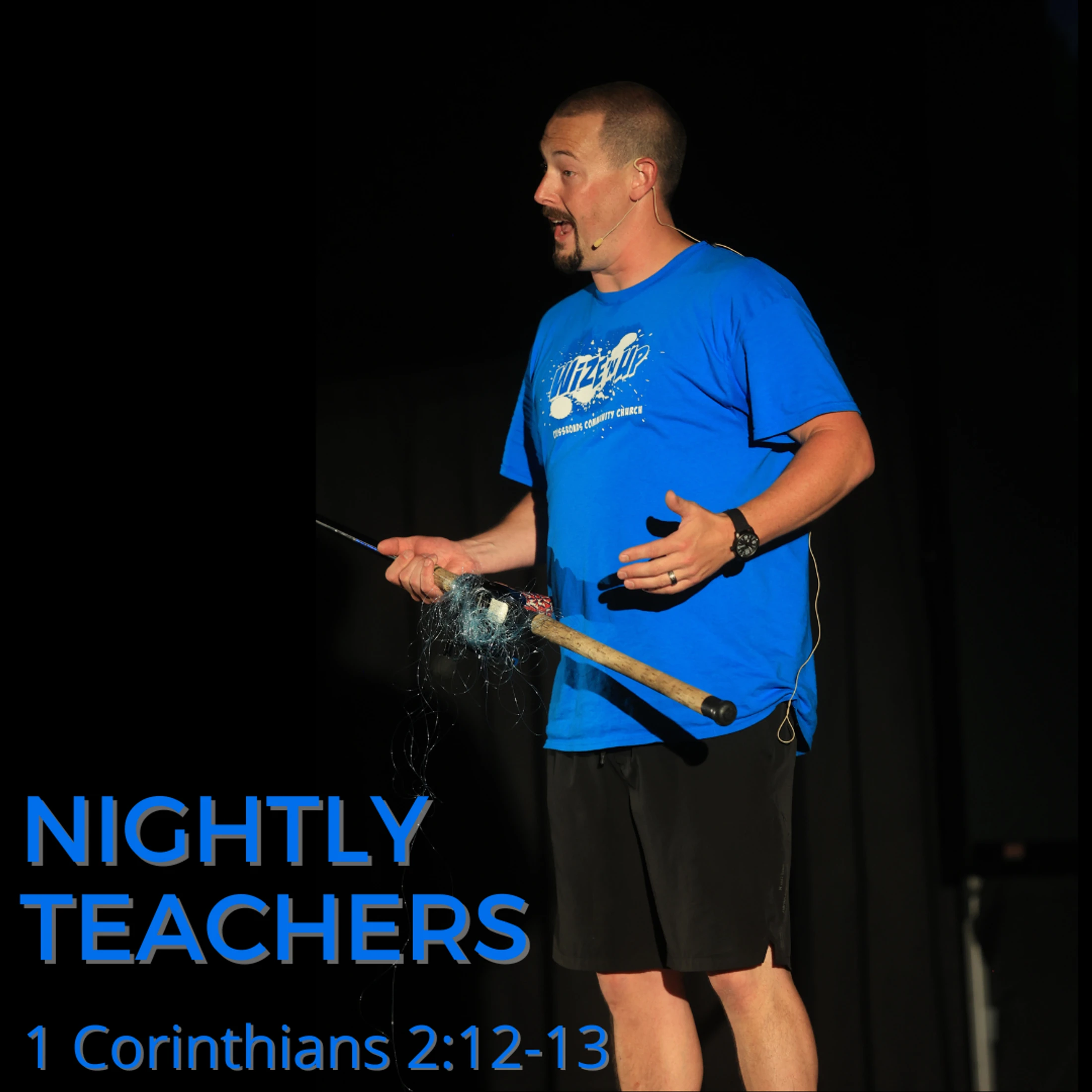 A man in a blue t-shirt speaks on stage holding a prop. Blue text at the bottom reads 'Nightly Teachers' and '1 Corinthians 2:12-13'.