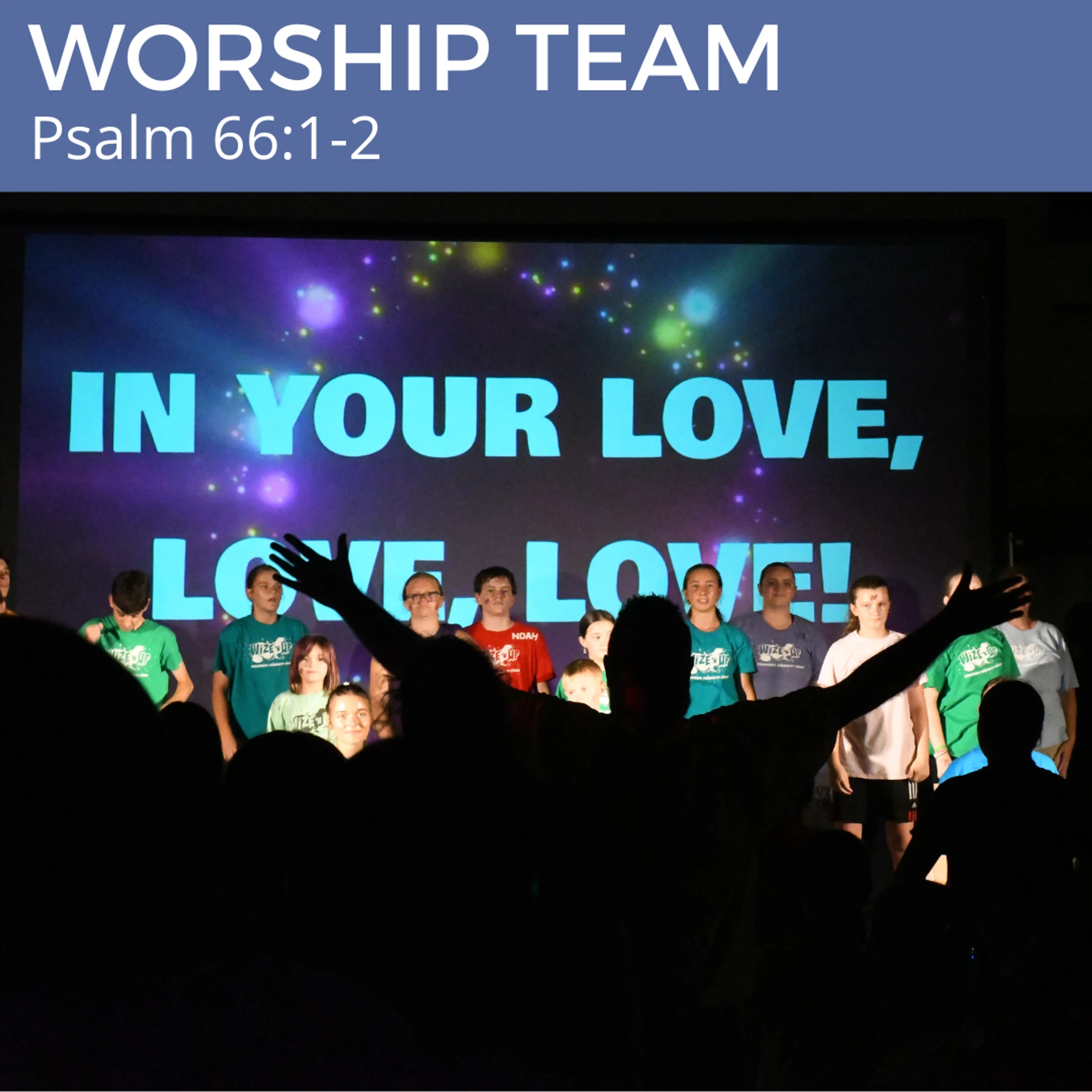 A person in the audience raises their hands in worship as a youth choir sings on stage. A screen behind them reads, 'In your love, love, love!'