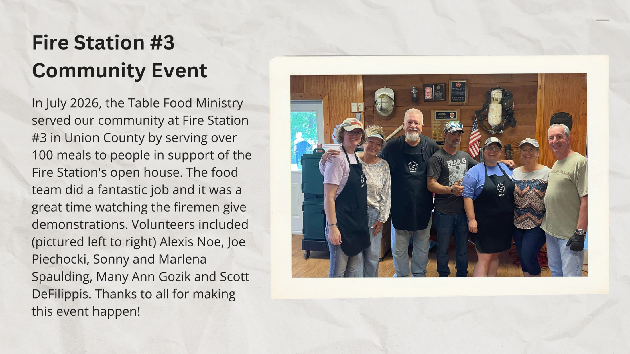 A group of seven volunteers from the Table Food Ministry smile for a photo inside a fire station during a community event.