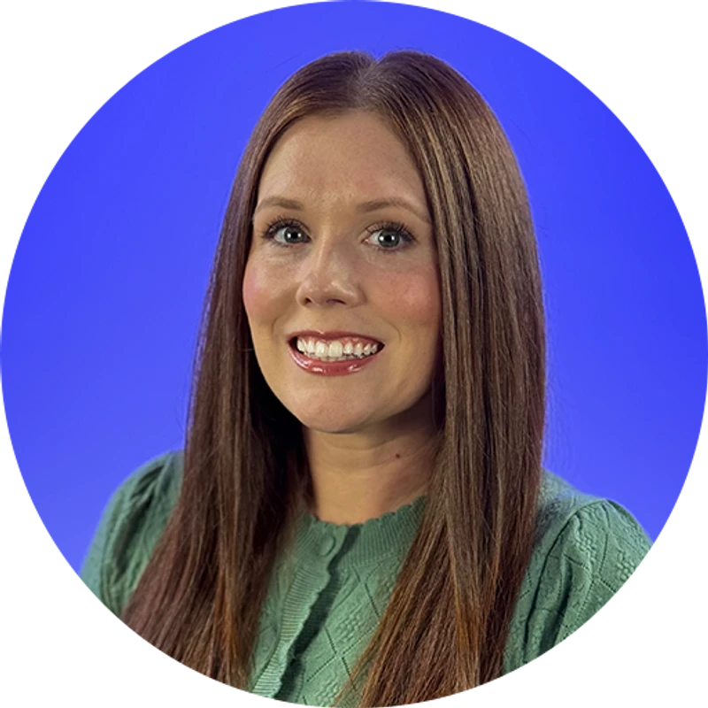 A circular headshot of a smiling woman with long brown hair, wearing a light green cardigan against a solid blue background.