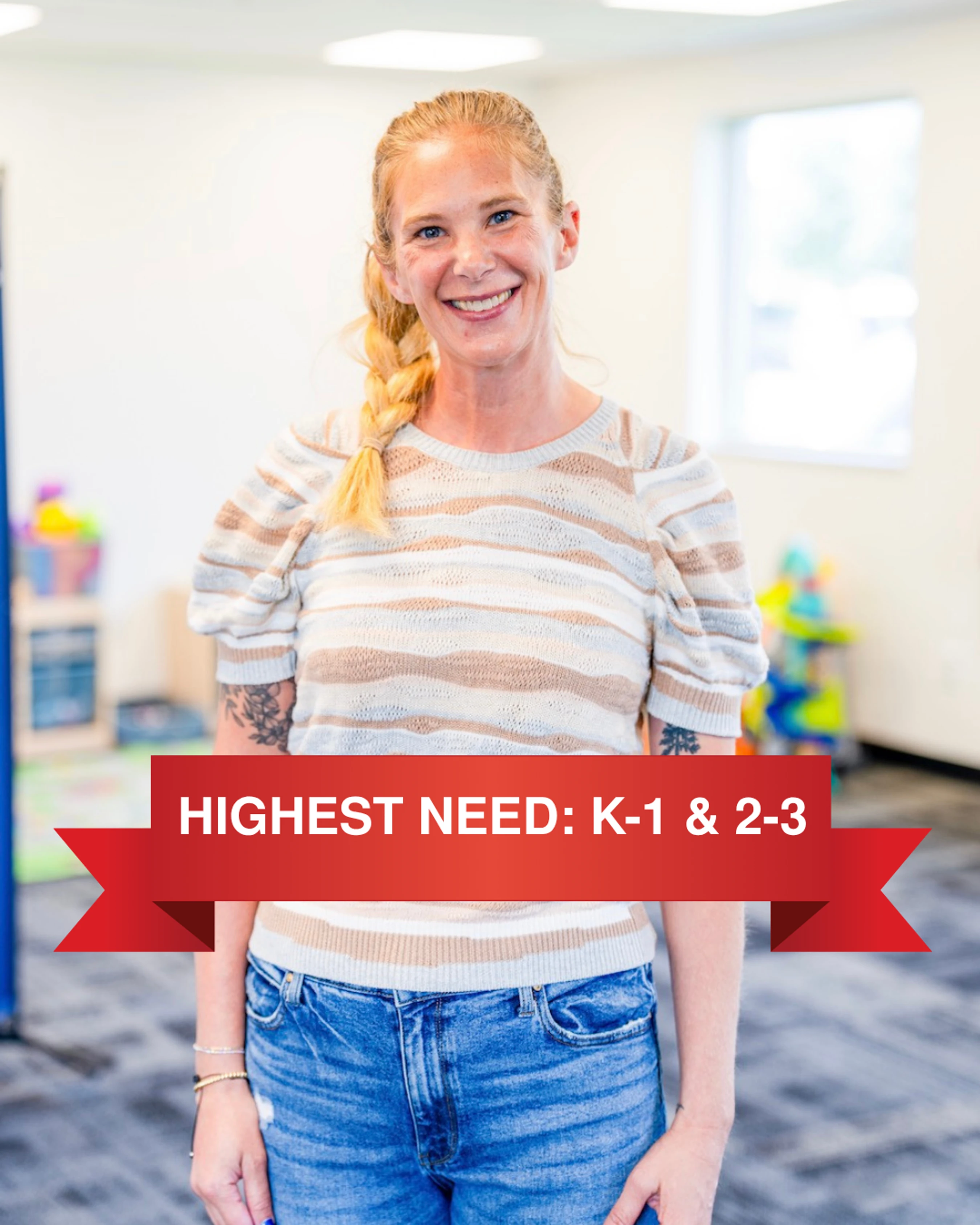 A friendly woman with a blonde braid stands in a classroom. A red banner across the photo reads 'HIGHEST NEED: K-1 & 2-3', seeking teachers or volunteers.