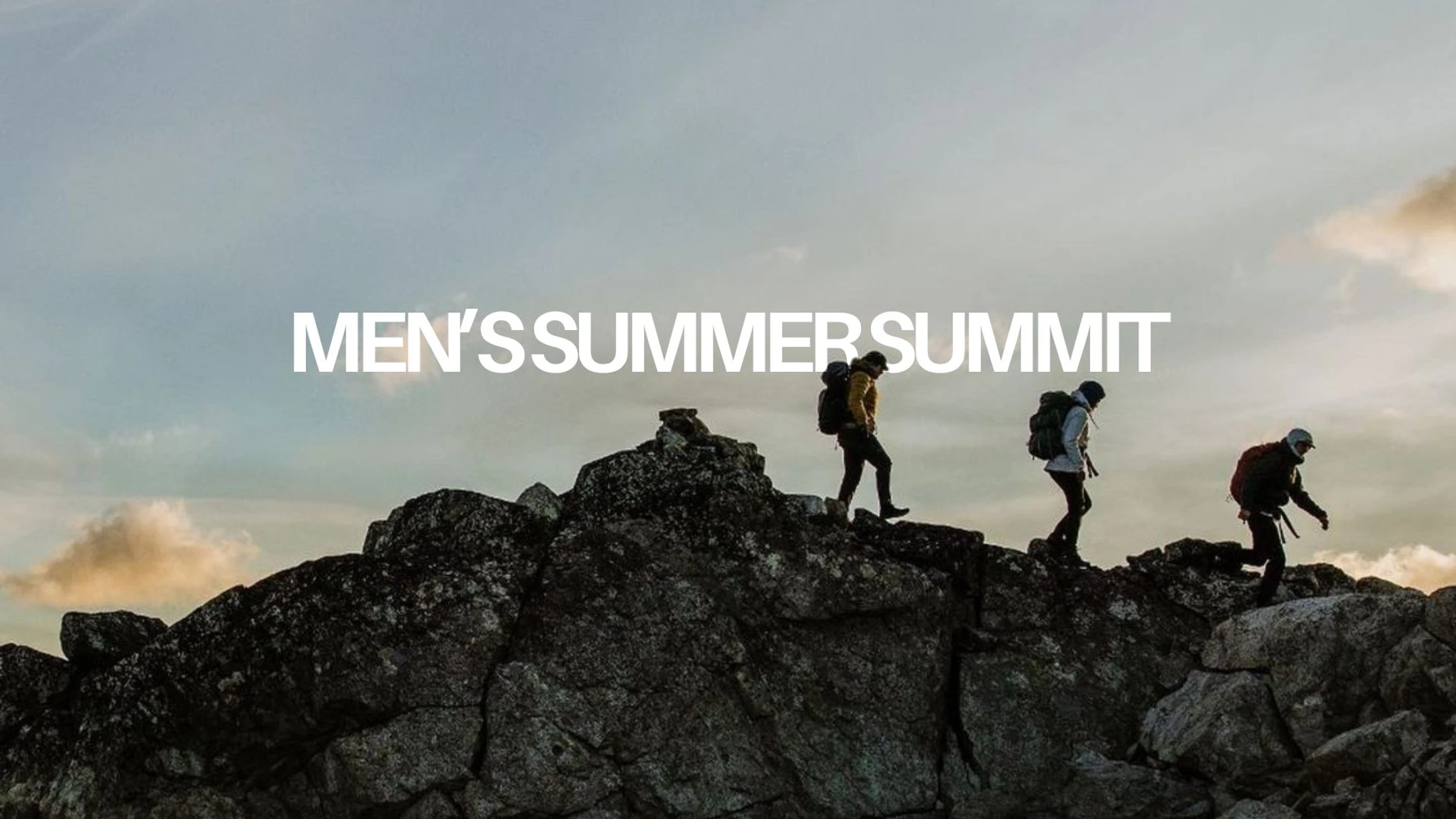 Three men wearing backpacks are silhouetted as they hike along a rocky mountain summit against a cloudy sky. Text reads: MEN'S SUMMER SUMMIT.