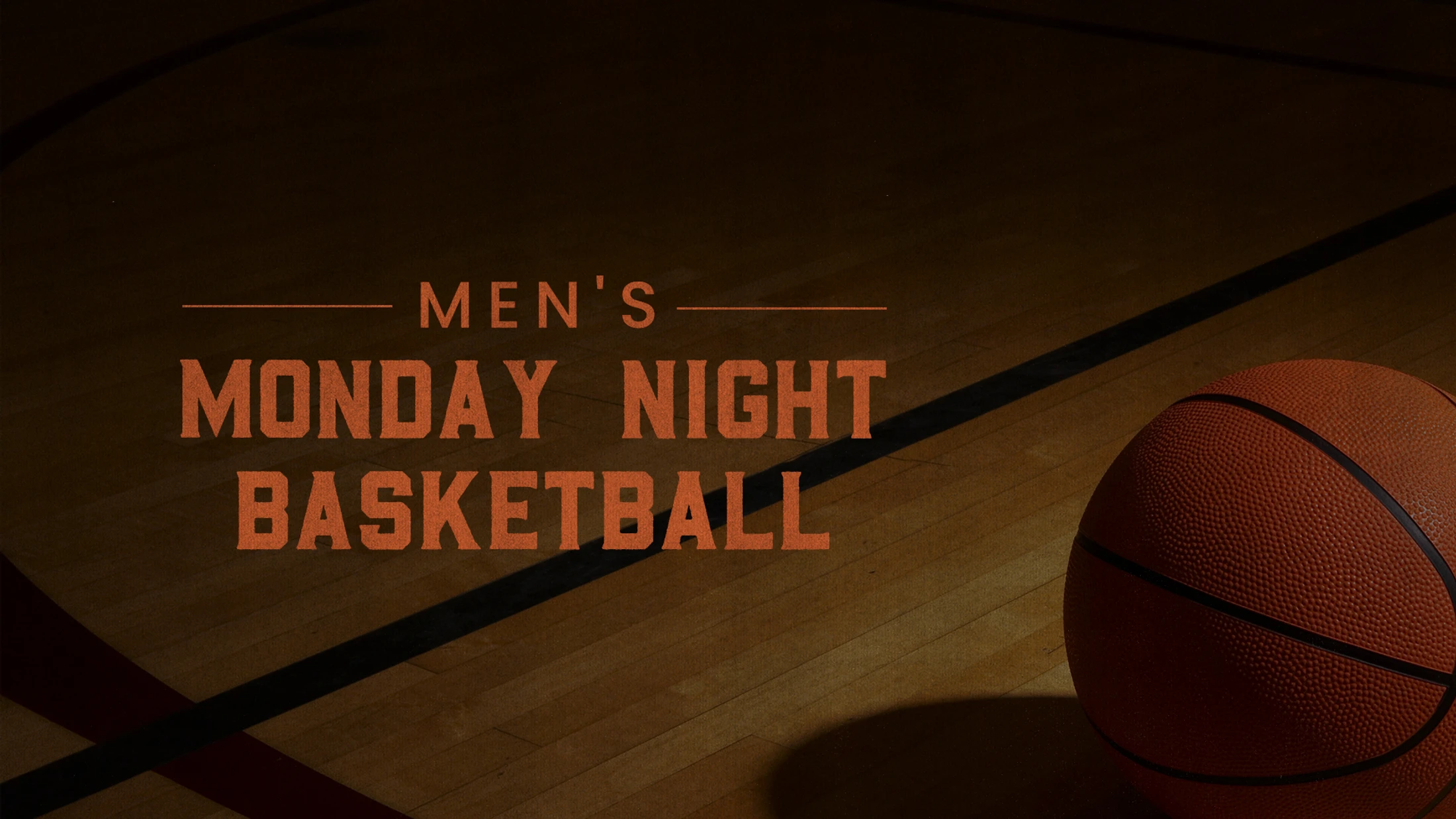 A basketball rests on a wooden court floor next to orange text that reads "Men's Monday Night Basketball".