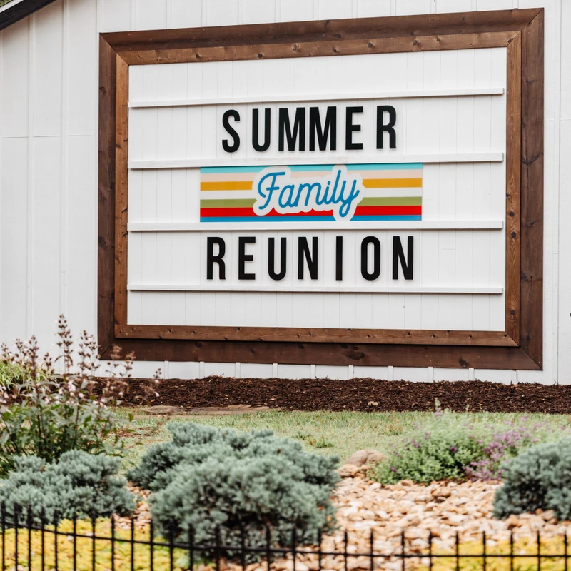 A large letterboard sign on a white building reads 'Summer Family Reunion.' The word 'Family' is in a colorful, retro style script.