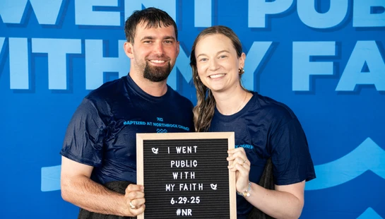 A smiling man and woman with wet hair and clothes hold a letter board that reads, "I went public with my faith 6.29.25," after being baptized.