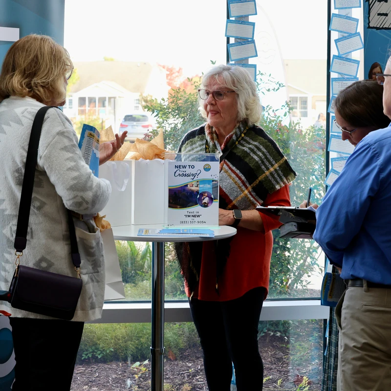 People at a Connect information table with brochures and a gift bag at The Crossing church