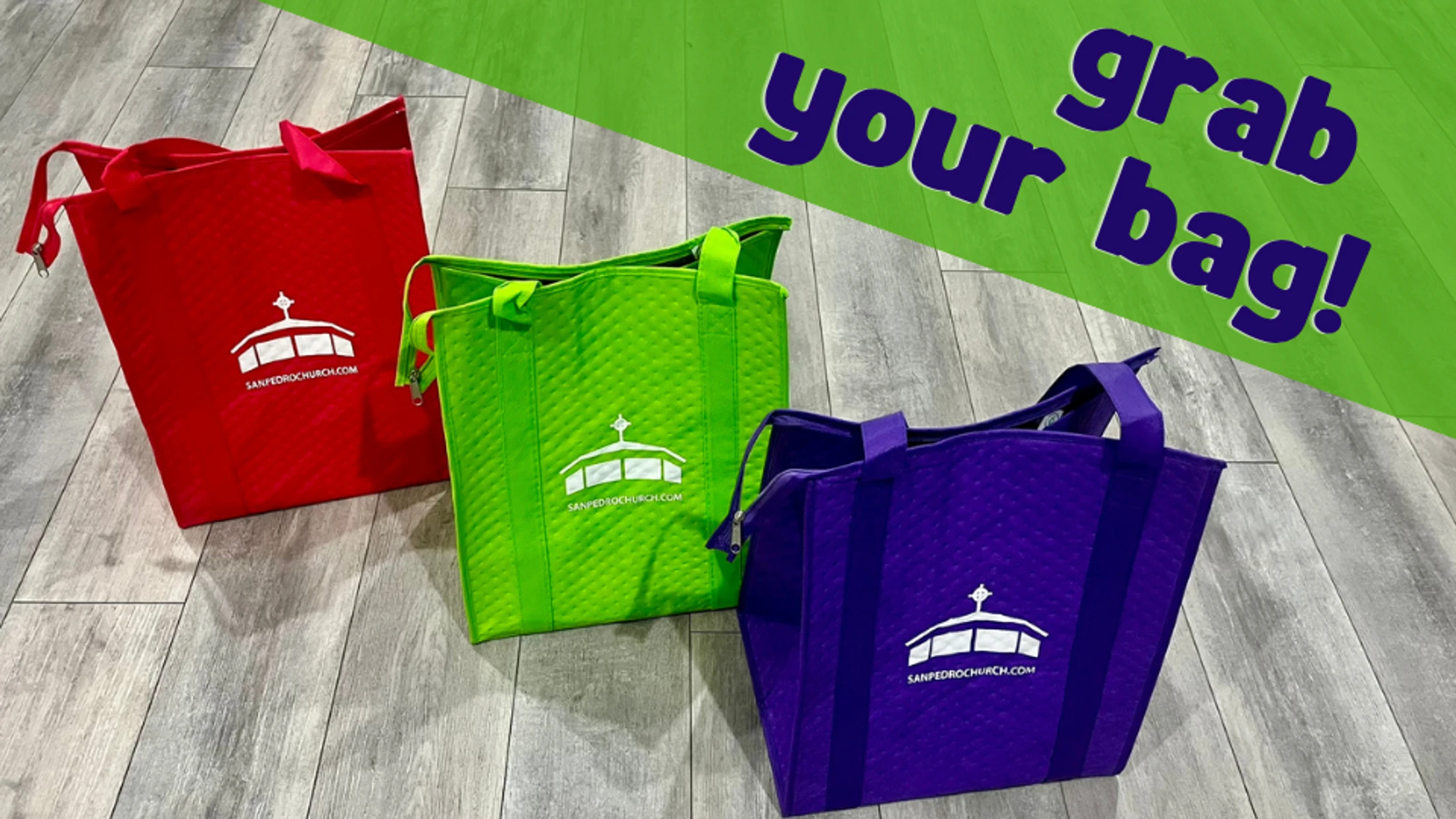 Three colorful tote bags in red, green, and purple with the San Pedro Church logo on a wood floor. A green overlay has the text 'grab your bag!'.