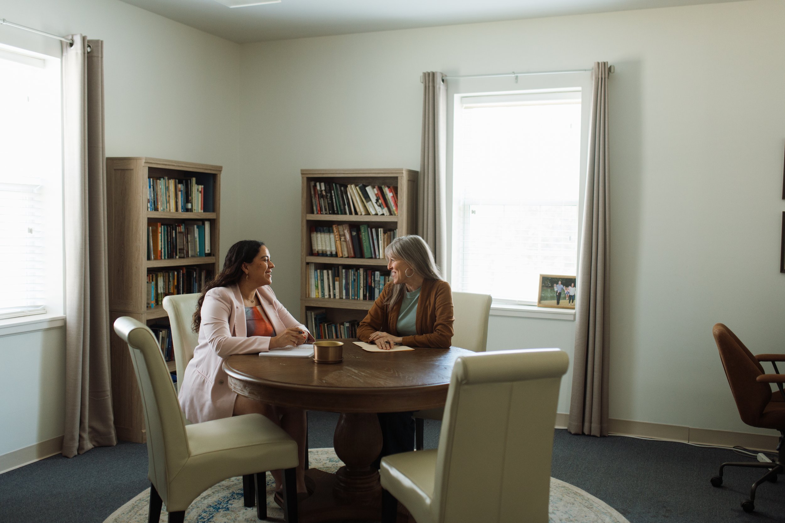Two women seated at a conference table in conversation.