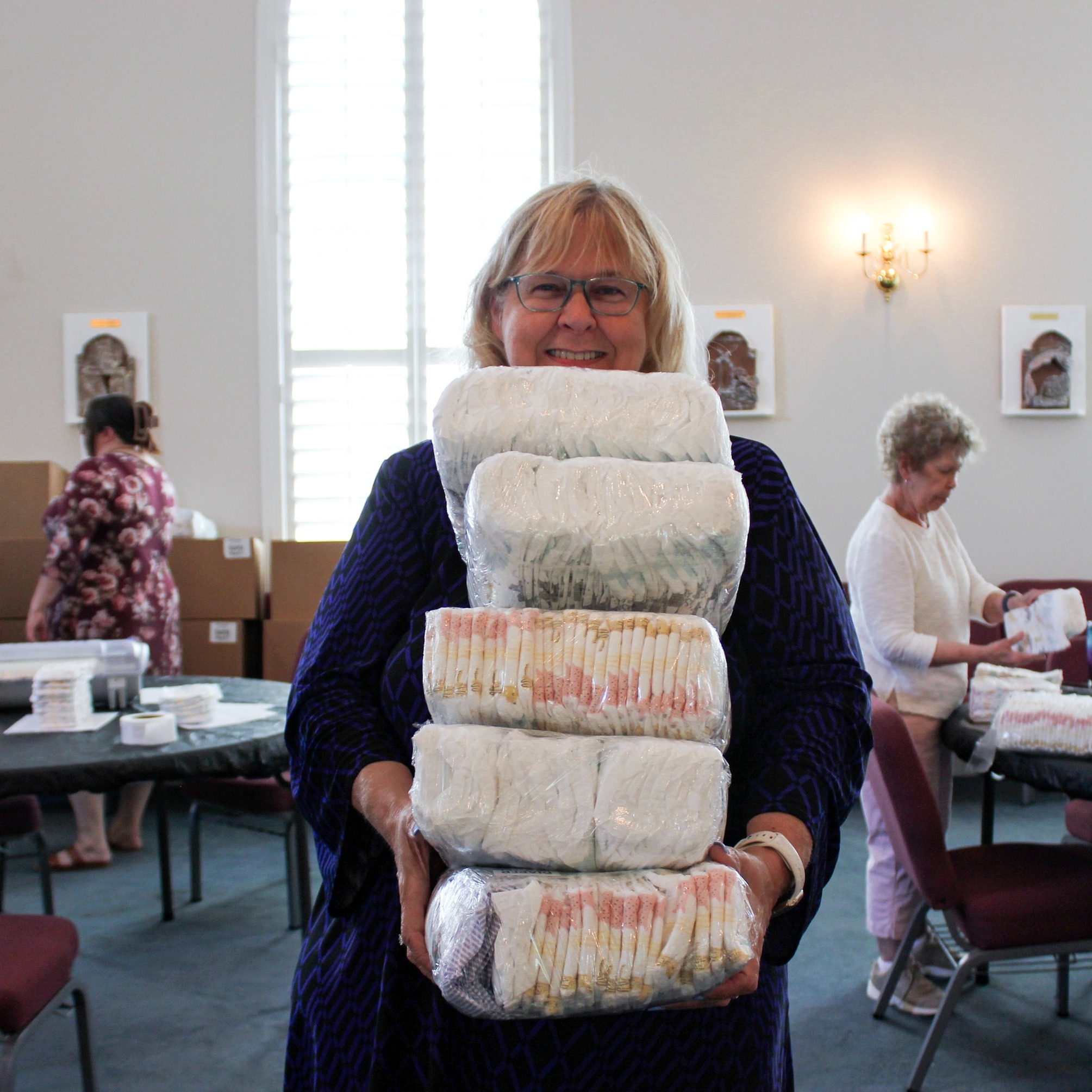 Woman holding wrapped diapers in a ministry setting.