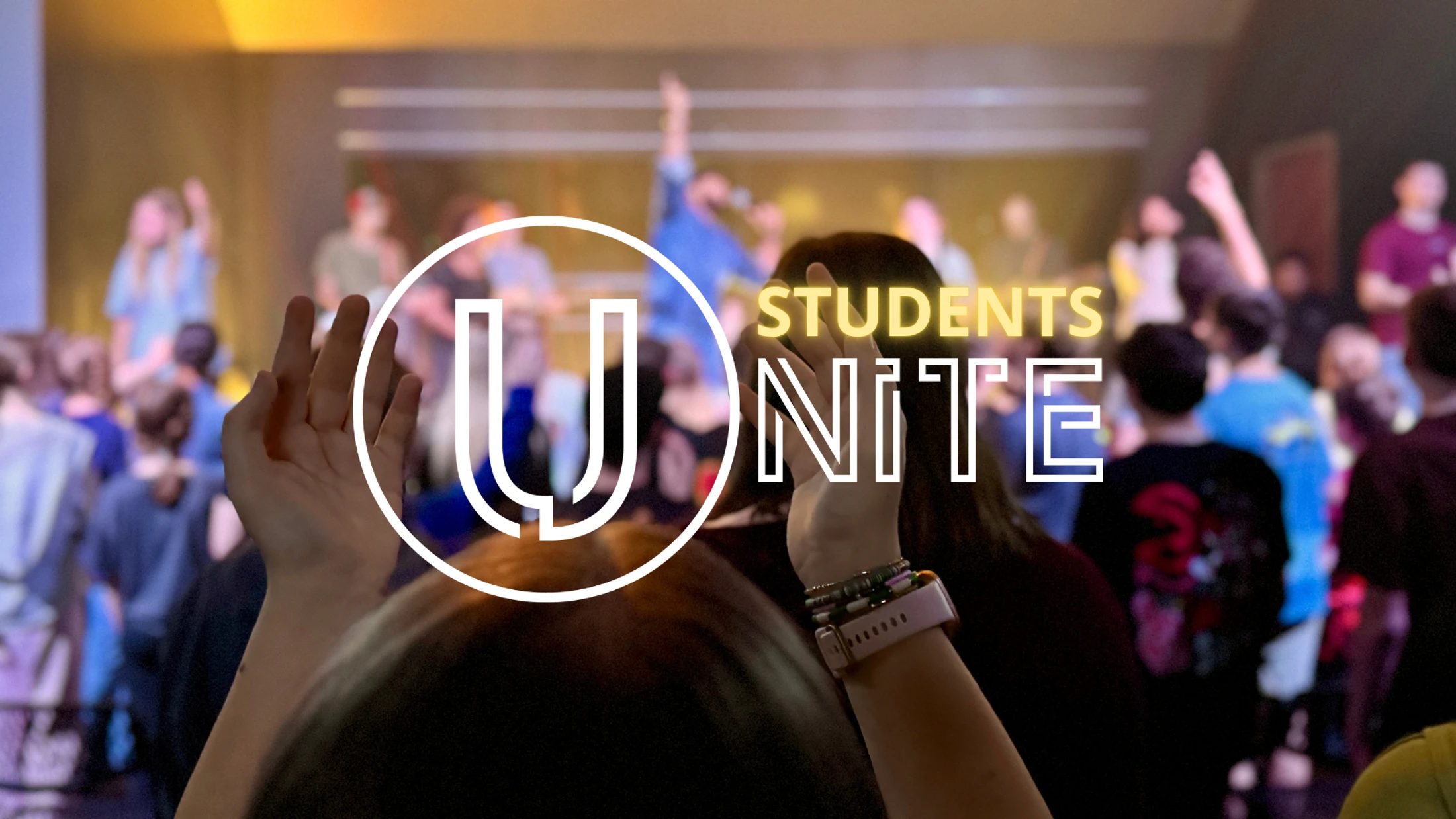 A crowd of students worships with hands raised at an event. A graphic overlay reads 'Students Unite' with a large stylized 'U' logo.