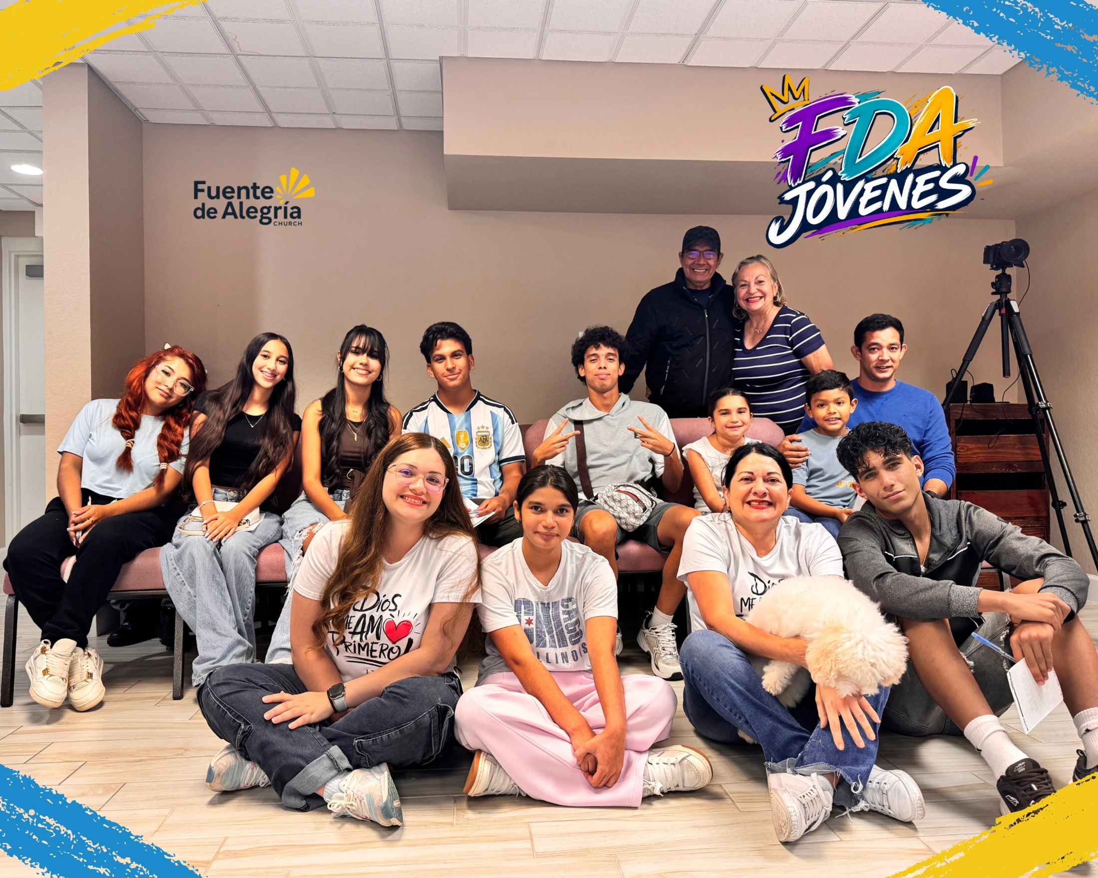 A large, diverse group of teenagers and adults from the Fuente de Alegría church youth group smiling together for a photo in a room.