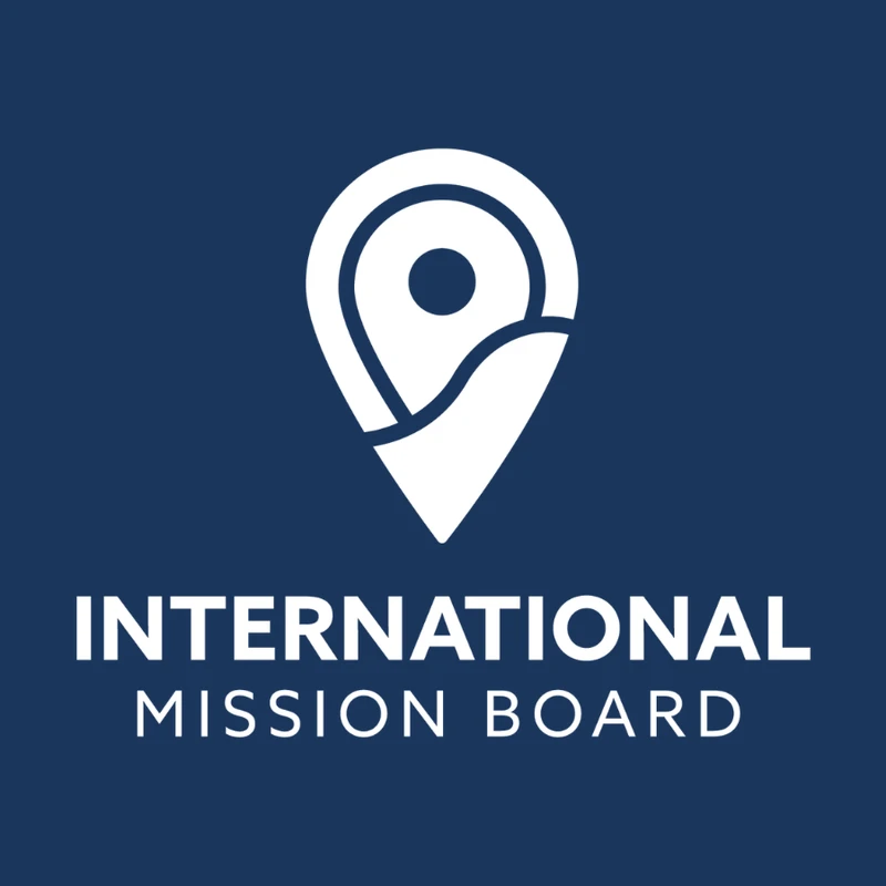 The International Mission Board logo on a dark blue background. The logo features a white map pin icon above the organization's name in white text.