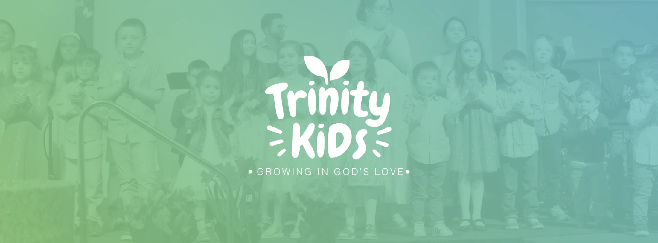 A group of children stand on a stage with a green and blue color overlay. A white logo reads 'Trinity Kids' and 'Growing in God's Love'.