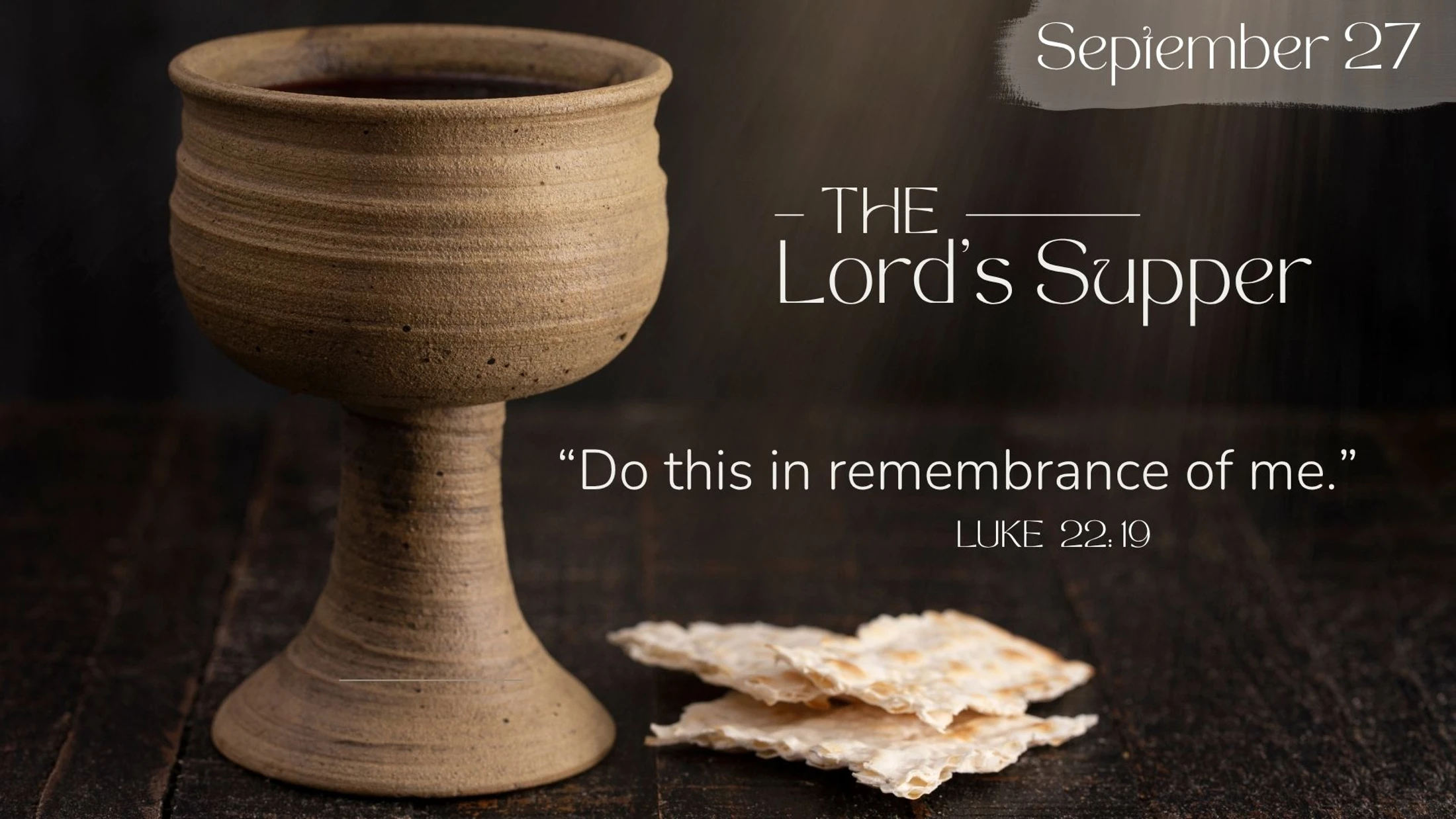A rustic chalice of wine and broken unleavened bread on a dark wood table. Text reads: The Lord's Supper, "Do this in remembrance of me." Luke 22:19.